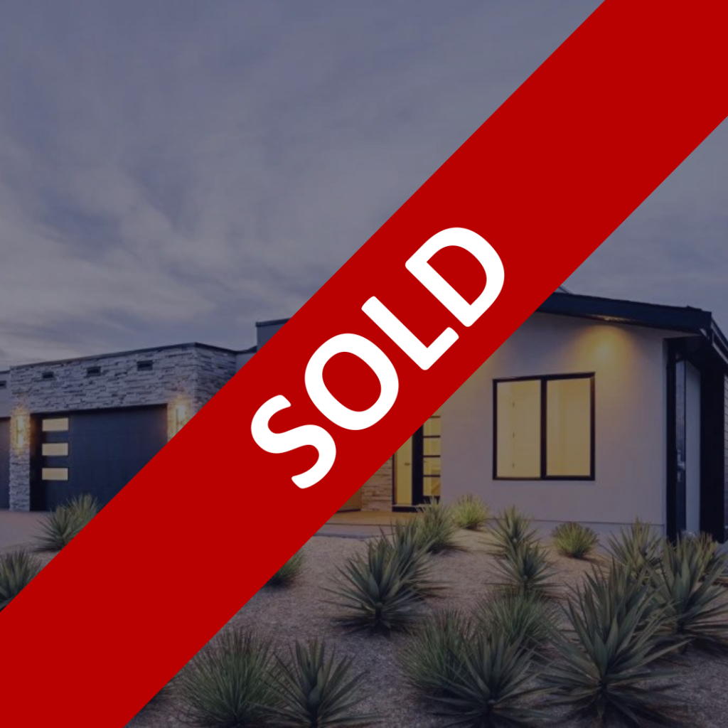 Modern house with a "SOLD" banner across the image. The house features a contemporary design with large windows and desert landscaping in the front yard.