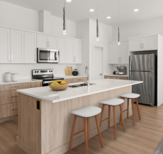 A modern kitchen with light wood flooring, white cabinets, stainless steel appliances, and a large island with three stools. The space is well-lit with pendant lights and includes a colorful wall art.